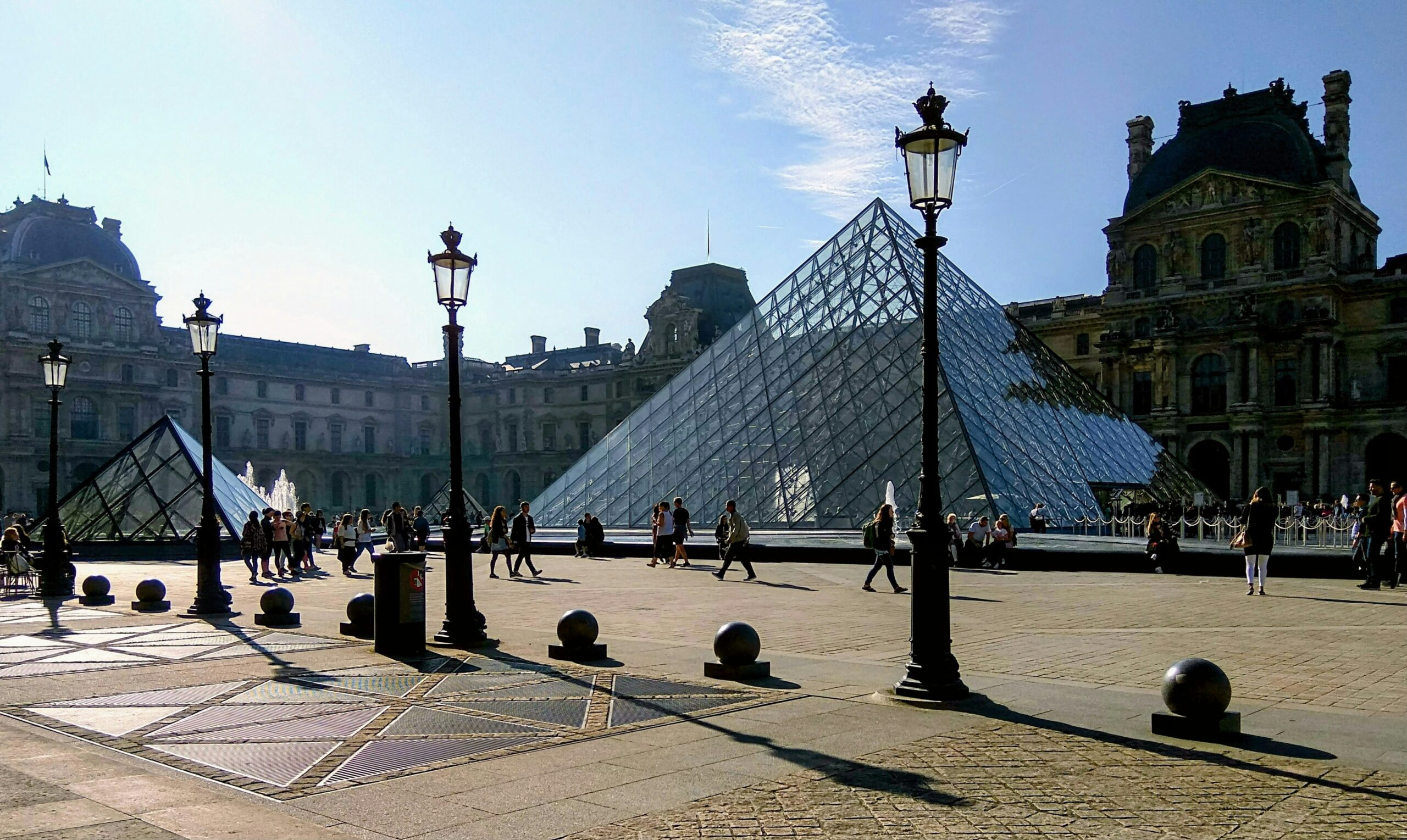 a group of people walking around a courtyard next to a pyramid